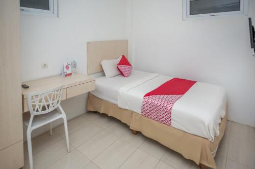 a bedroom with a bed and a desk and a chair at Hotel O Lapan Lapan in Banjarmasin