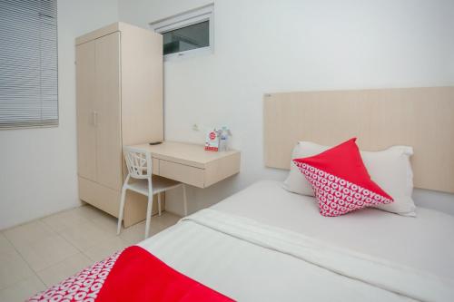 a bedroom with a bed with red and white pillows at Hotel O Lapan Lapan in Banjarmasin
