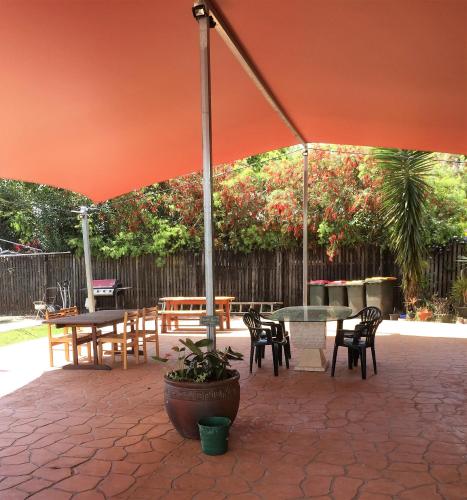 a patio with tables and chairs under an umbrella at Curtain Fig Motel in Yungaburra