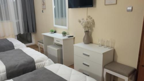 a bedroom with two beds and a desk with a vase of flowers at Victoria Family Hotel in Balchik