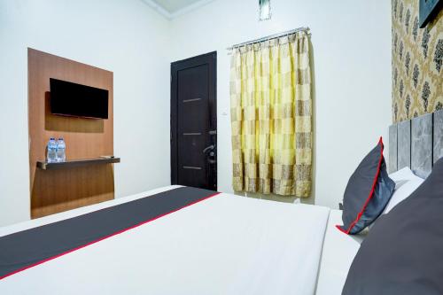a bedroom with a bed and a tv on a wall at Hotel O Padang City Center Near Pantai Padang Formerly D'Dhave Hotel in Padang