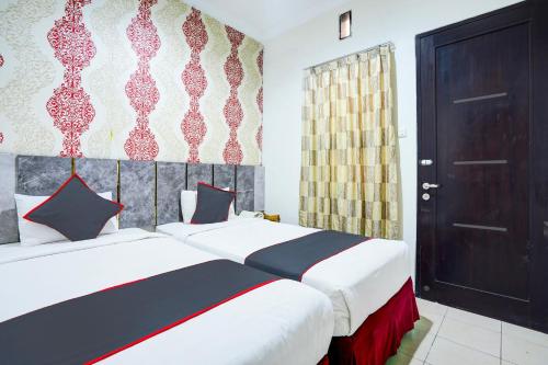 a bedroom with two beds and a door at Hotel O Padang City Center Near Pantai Padang Formerly D'Dhave Hotel in Padang