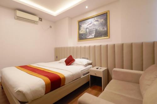 a bedroom with a bed and a chair at Capital O Palagya Hotel Pvt Ltd in Pashupatināth