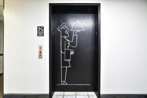 a black elevator door with a drawing of a man and a woman at OYO Townhouse Inn Jacksonville near Little Rock Air Force Base in Jacksonville
