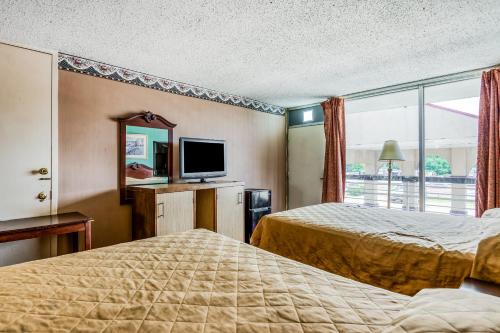 a hotel room with two beds and a television at OYO Hotel Jackson North I-55 in Jackson