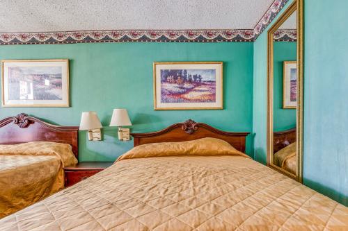 a bedroom with two beds and a mirror at OYO Hotel Jackson North I-55 in Jackson