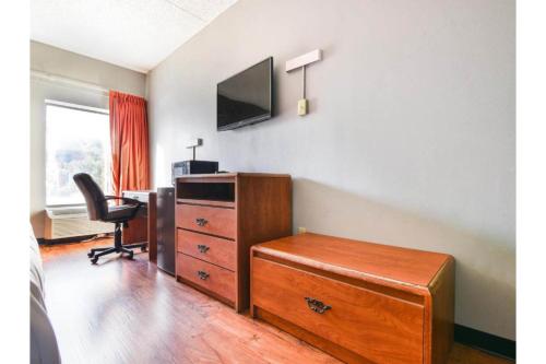 a room with a dresser and a tv and a chair at OYO Townhouse Inn Jacksonville near Little Rock Air Force Base in Jacksonville