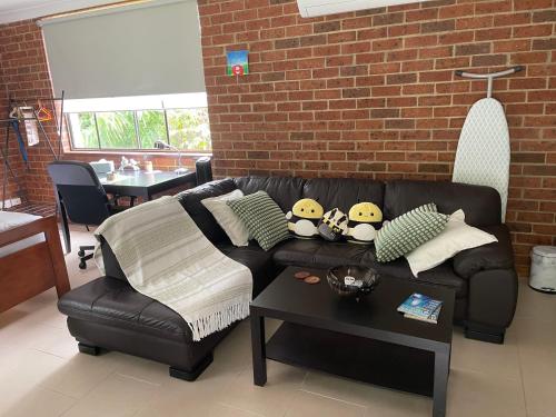 a living room with a black leather couch and a table at Garden Hideaway-Entirely Private in Beecroft