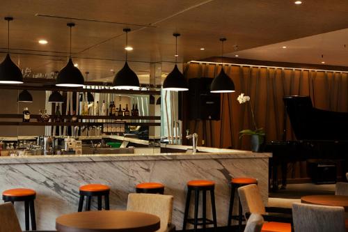 a bar with orange stools in a restaurant at Grand Diamond Hotel Yogyakarta - Formerly Grand Quallity Hotel in Yogyakarta