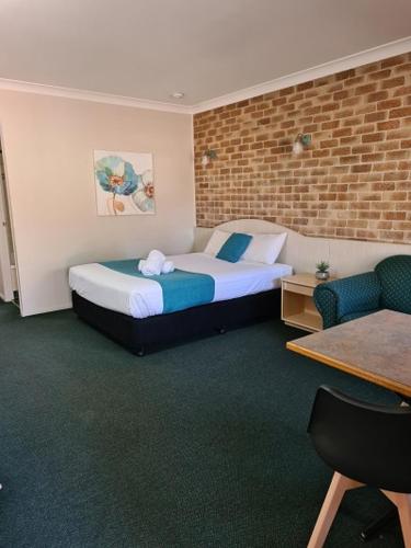 a hotel room with a bed and a chair at Country Gardens Motor Inn in Toowoomba