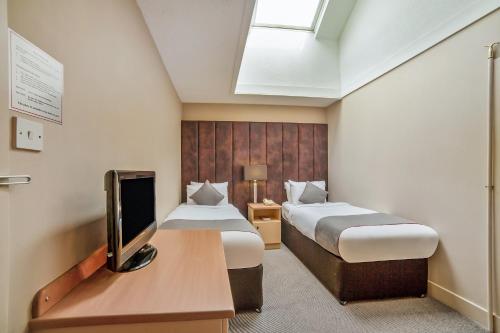 a hotel room with two beds and a tv at Brentwood Aberdeen City Centre near Union Street in Aberdeen