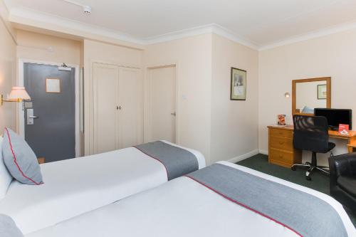 a hotel room with two beds and a desk at OYO Stade Court Hotel in Hythe