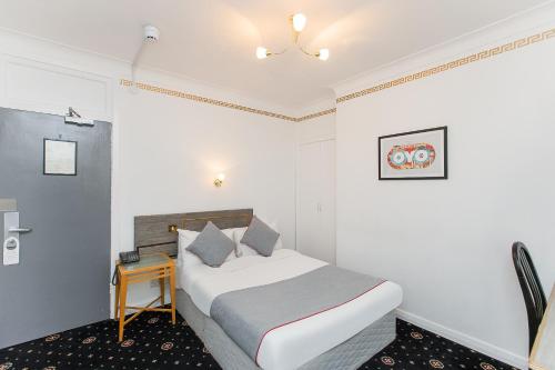 a bedroom with a bed and a small table at OYO Stade Court Hotel in Hythe