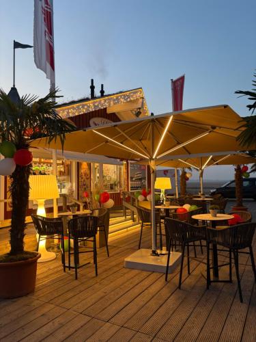 a restaurant with tables and umbrellas on a deck at Großzügiges Apartment in Strandnähe im Herzen St. Peter-Ordings in Sankt Peter-Ording