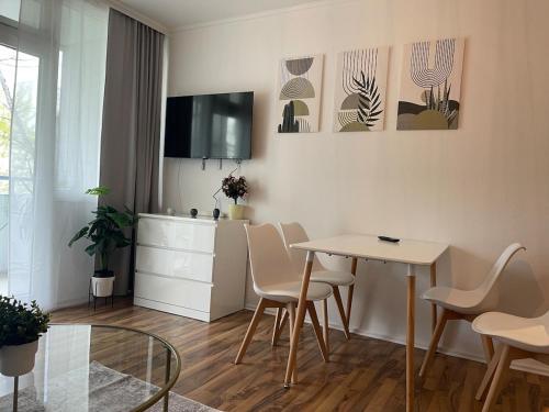 un soggiorno con tavolo, sedie e TV di Charmantes Familienrefugium im Zentrum von Ludwigshafen - Eleganz & Komfort Ideal fur Familien a Ludwigshafen am Rhein
