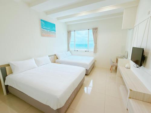una camera d'albergo con due letti e una televisione di MuyuTime B&B a Green Island