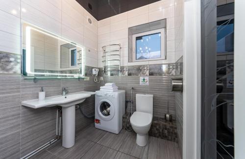 a bathroom with a toilet sink and a washing machine at Viktoriya Family 2 Country complex in Kyiv