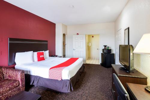 a hotel room with a bed and a flat screen tv at OYO Hotel LSU in Port Allen