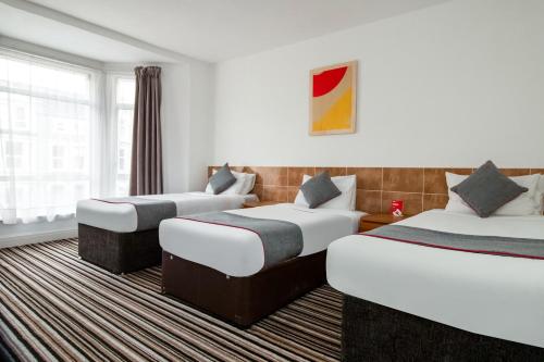 a hotel room with three beds and a window at Cardiff Riverside Hotel by Belvilla in Cardiff