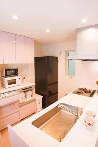 a kitchen with white cabinets and a black refrigerator at 全新设备设施 3层102平方独栋洋房4室1厅2卫2个洗澡间 厨房完备 交通便利 in Tokyo