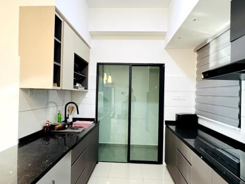 a kitchen with black countertops and a glass door at Sunshine Residence Kekloksi View 2R 4pax in Ayer Itam