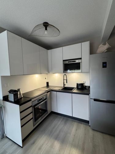 une cuisine avec des armoires blanches et un réfrigérateur en acier inoxydable dans l'établissement Ajaccio Sanguinaires T3 proche Trottel et 150m de la mer, belle résidence, à Ajaccio