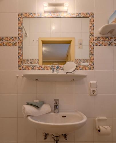 a bathroom with a sink and a mirror and towels at Hotel Wiesbaden in Wenningstedt