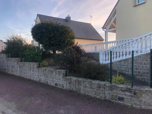 a retaining wall in front of a house with a fence at Gîte Argouges in Argouges
