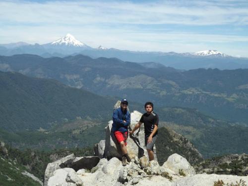 two men standing on the top of a mountain at Cabañas Los Canelos Pucon, Hermosa Granja de 20 hectaréas a orillas del Río Liucura in Pucón
