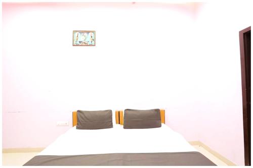 a bed in a white room with two pillows at HOTEL SUPERIOR DEV VILLA Near City Park Jaipur in Jaipur
