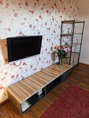 a flat screen tv on a wall with flowers at Suur-Sadama Apartment in Kuressaare