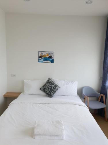 a bedroom with a white bed and a chair at Sandy hotel in Krabi town