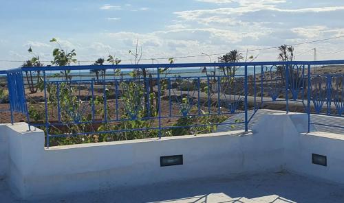 a balcony with a blue railing with a view of the ocean at Villa Yahia Djerba in Bou Menjel