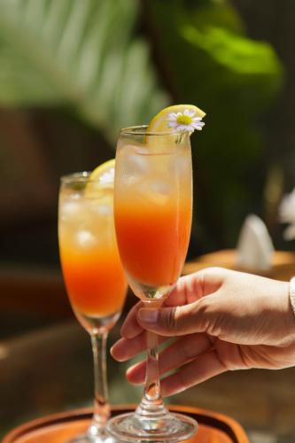 a person holding up two glasses of orange juice at Mamori House at Kohlarn in Ko Larn