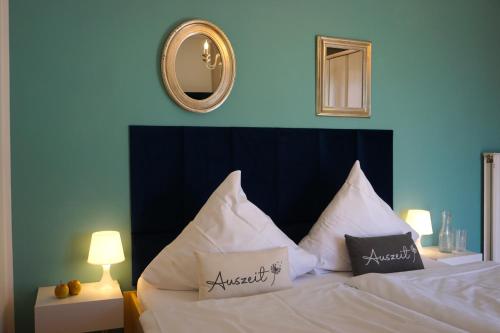 a bedroom with a bed with white pillows and a mirror at Apartment Kaiserperle mit Balkon direkt am Strand in Lübeck