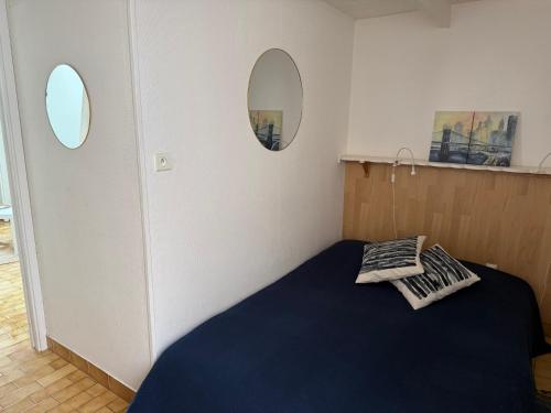 - une chambre avec un lit bleu et deux miroirs dans l'établissement Vue sur l'Etang de Thau, à Balaruc-les-Bains