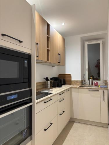 une cuisine avec des armoires blanches et un micro-ondes dans l'établissement STA4 Le Suquet, Proche Mer et Palais des Congrès, à Cannes