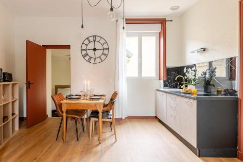 une cuisine avec une table et des chaises et une horloge au mur dans l'établissement Bronze, all comforts, hyper center 6P, à Roanne