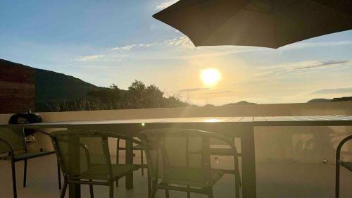 two chairs and an umbrella on a balcony with the sunset at Maison cosy in Sisco