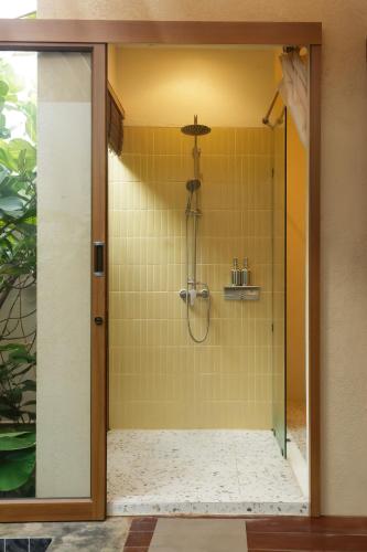 a shower in a bathroom with yellow tiles at Mamori House at Kohlarn in Ko Larn