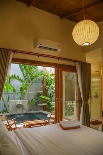 a bedroom with a bed and a window with a pool at Mamori House at Kohlarn in Ko Larn