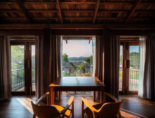 a dining room with a table and chairs and a large window at Nachan The Antique Courtyard in Chiang Khan