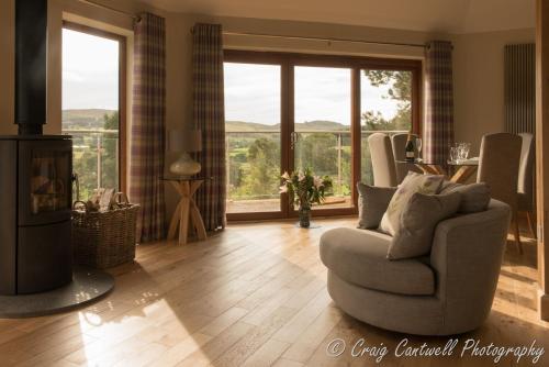 a living room with a chair and a fireplace at Scots Pine Treehouse in Glenshee
