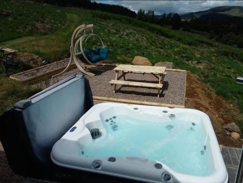 a bath tub sitting on top of a hill with a picnic table at Scots Pine Treehouse in Glenshee