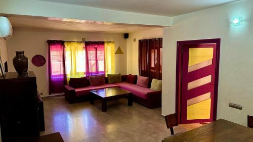 a living room with a red couch and colorful windows at Villa DARANA in Douaïra