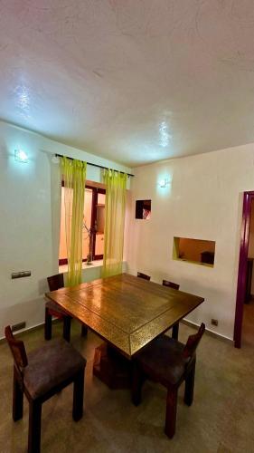 a dining room with a wooden table and chairs at Villa DARANA in Douaïra