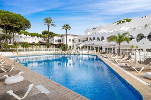 a pool at a resort with lounge chairs and palm trees at Casa Marbella Vime Resort Gym Spa Pools in Marbella