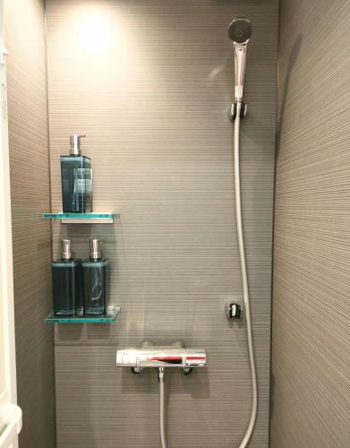 a bathroom with a shower with two shelves on the wall at CITY OASIS Harajuku, Shinjuku, Shibuya in Tokyo