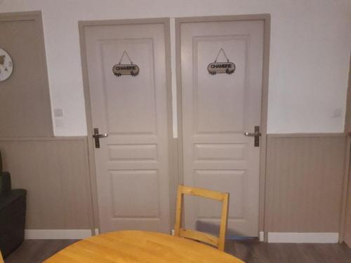 - deux portes dans une chambre avec une table et une chaise dans l'établissement Appartement , 500 m de la mer, à Le Portel