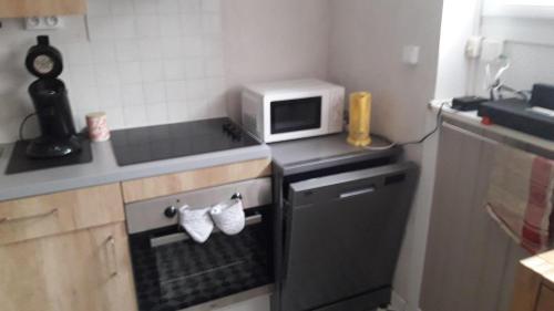une cuisine avec une cuisinière et un micro-ondes dans l'établissement Appartement , 500 m de la mer, à Le Portel
